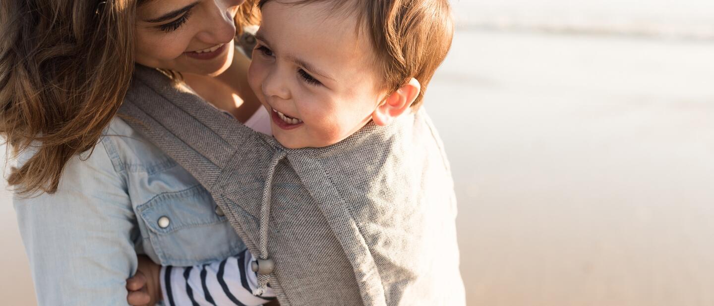 Vrouw met kind in draagzak op het strand