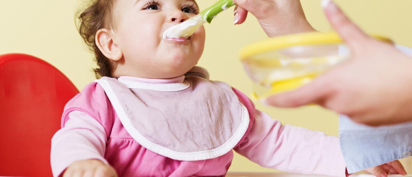 Baby in kinderstoel die een hapje eten krijgt