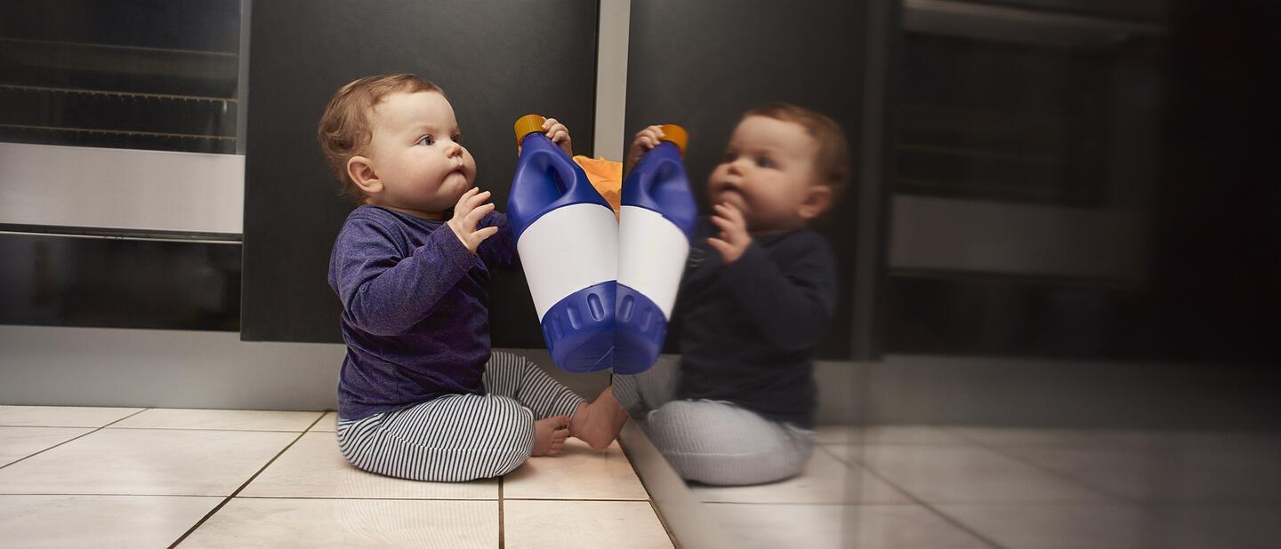 Baby speelt met fles schoonmaakmiddel
