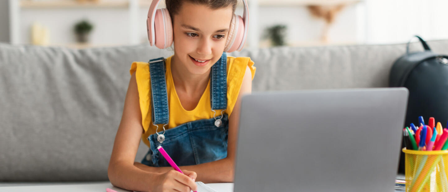 Kind met koptelefoon achter laptop
