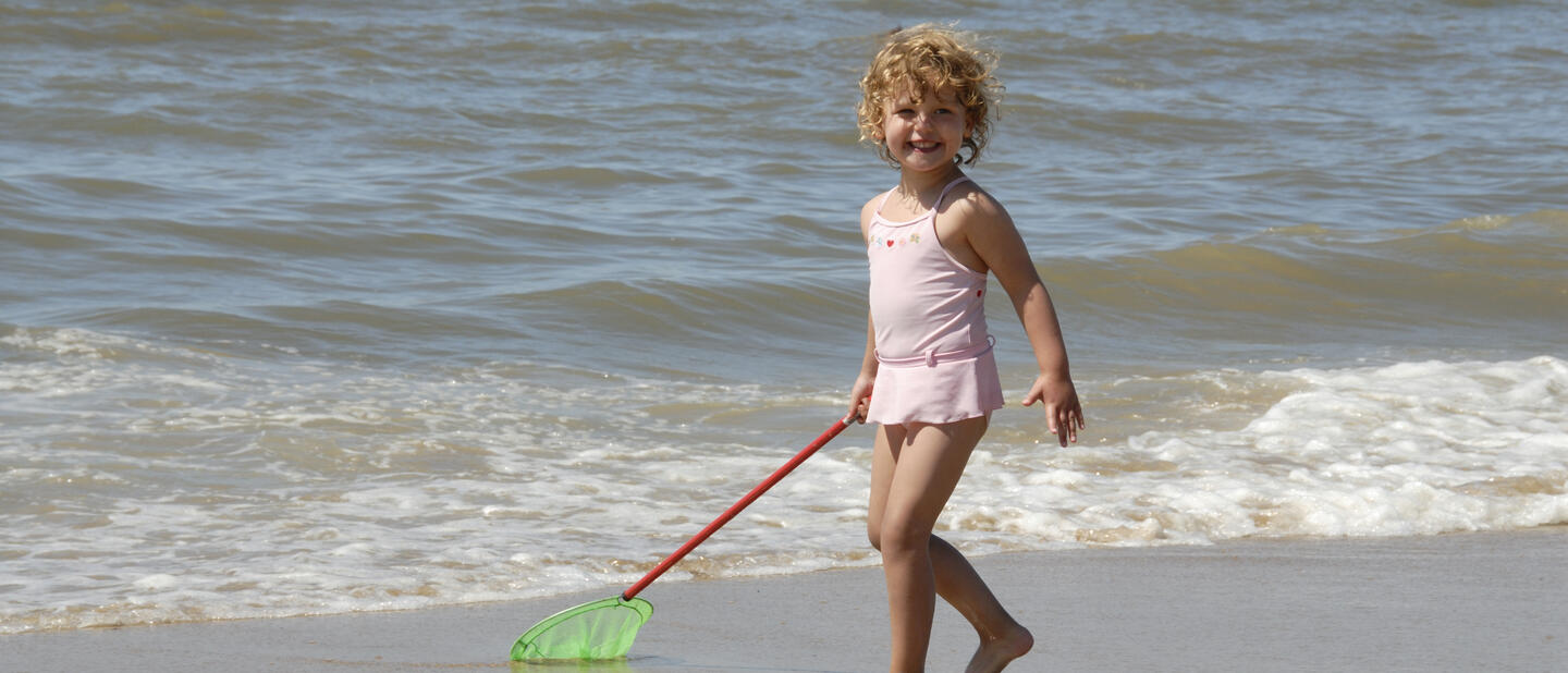 Meisje speelt aan zee in de branding