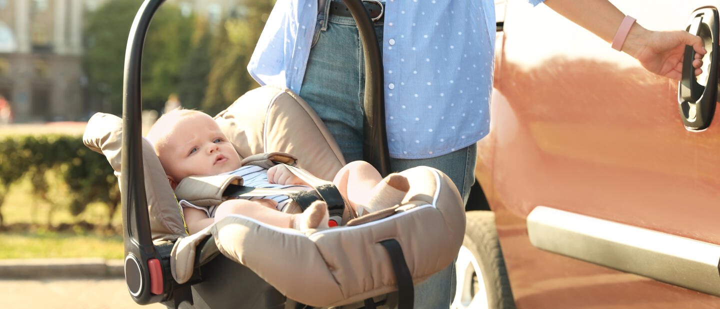 Baby in babyautostoel bij auto