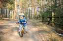 Jongetje op loopfiets in bos